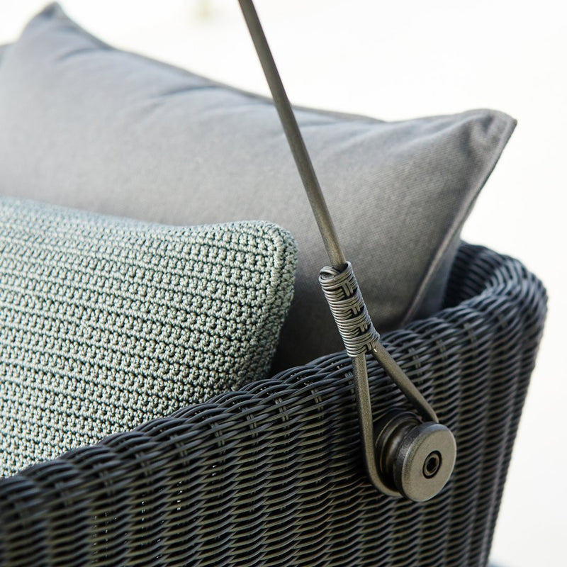 Textured teal and gray throw pillows on a dark woven chair, featuring subtle patterns and modern design elements.