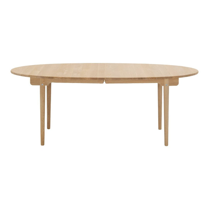 Light oak oval dining table with a smooth surface and minimalist design, featuring four tapered wooden legs.