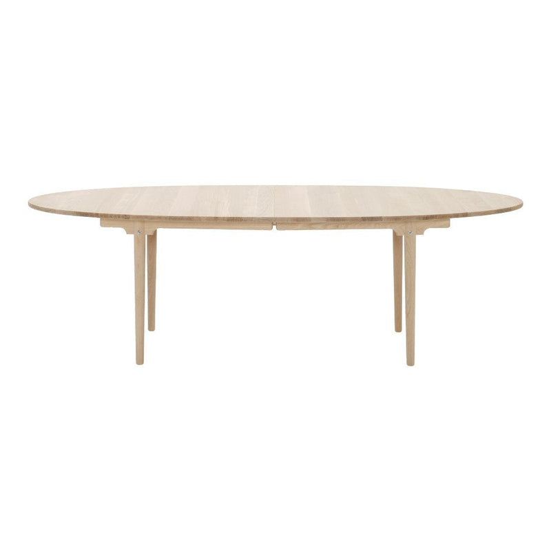 Light wood oval dining table with a smooth finish and minimalist design, showcasing natural wood grain patterns.