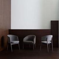 Gray upholstered chairs with sleek black wooden legs, set against a minimalist neutral backdrop.