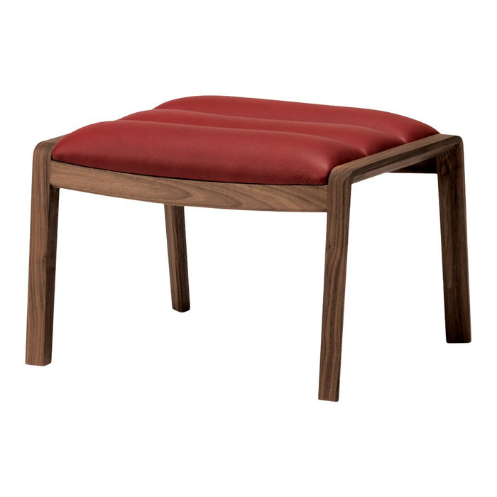 Red padded ottoman with a smooth, tufted surface and a sleek wooden frame. Perfect for modern decor.