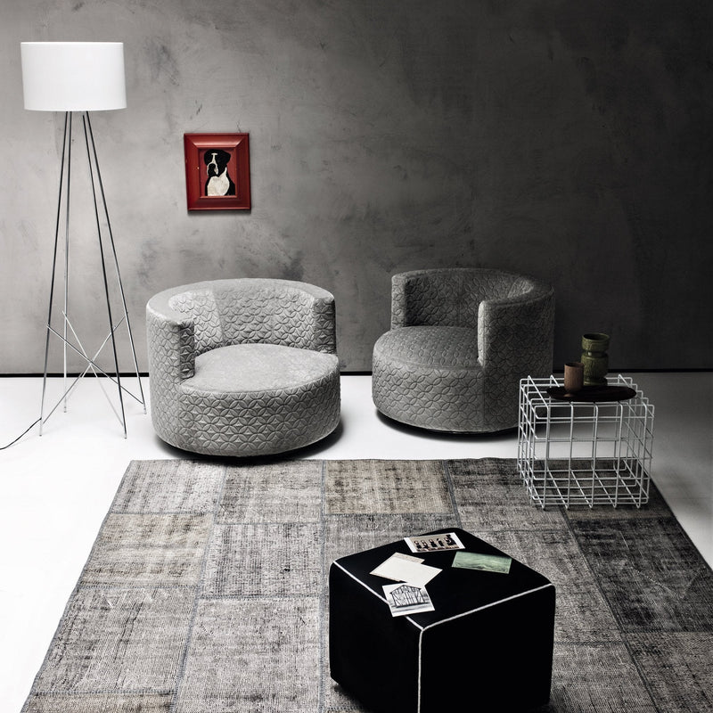 Cozy gray upholstered chairs with a quilted pattern against a minimalist backdrop featuring a textured rug.