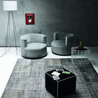 Smooth gray patterned chairs with a black ottoman and a textured gray rug, creating a modern interior aesthetic.