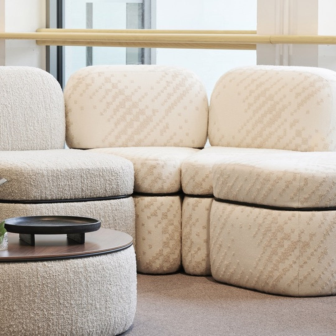 Textured cream upholstery with subtle geometric patterns on a modern sofa and ottoman set.