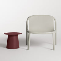 Modern light gray chair paired with a bold red side table, featuring smooth and minimalist designs.