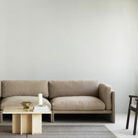 Beige sofa with textured fabric, complemented by a light wooden coffee table and subtle gray striped rug.