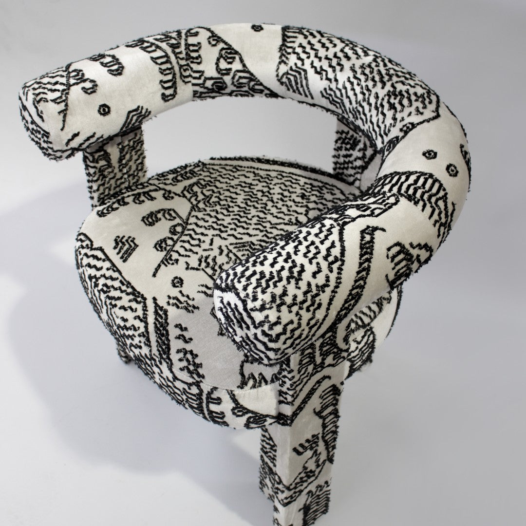 Black and white patterned chair with abstract designs and rounded arms, enhancing modern decor.
