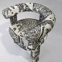 Black and white patterned chair with abstract designs and rounded arms, enhancing modern decor.