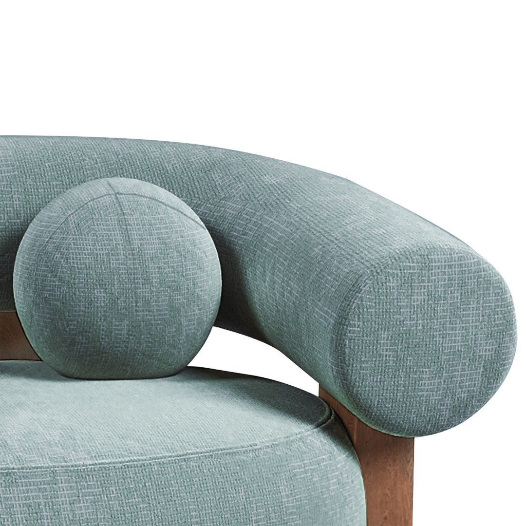 Soft green upholstery with textured patterns on a rounded chair arm and cushion, featuring a matching spherical accent.
