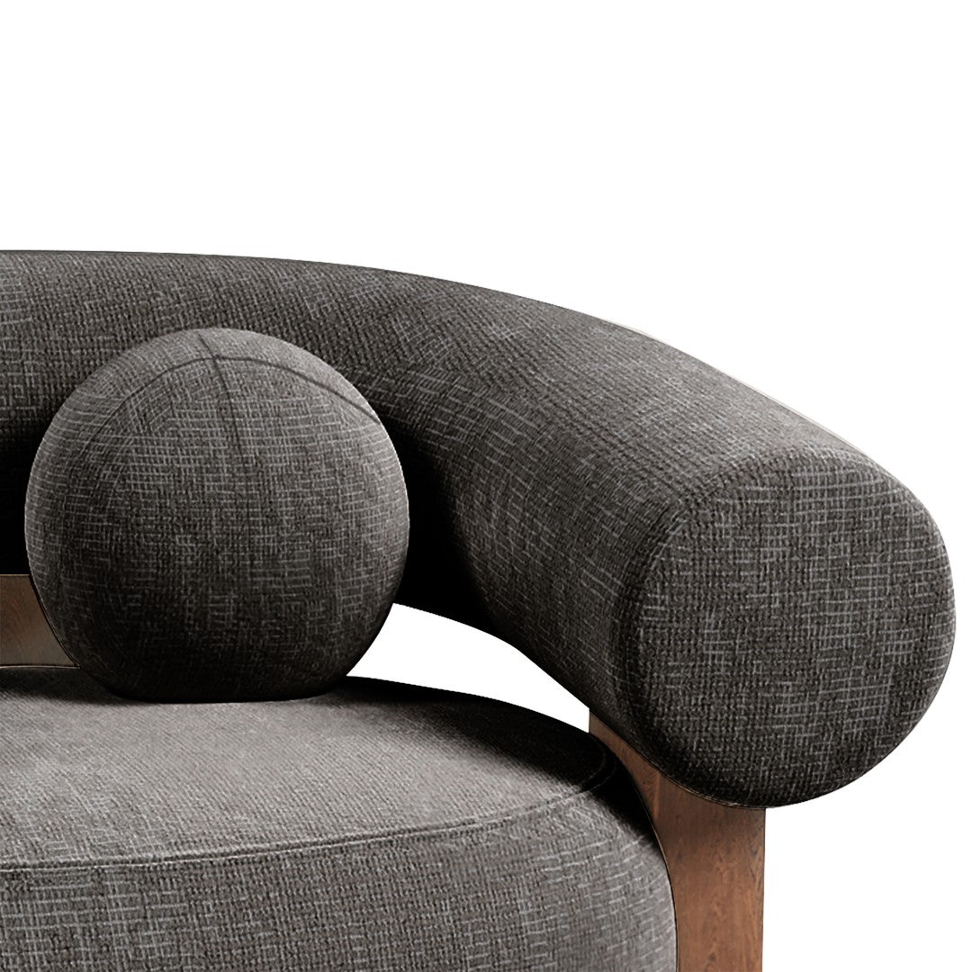 Curved grey sofa arm with textured fabric and matching round cushion, showcasing a modern minimalist design.