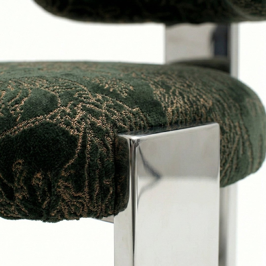 Green and gold patterned upholstery on a chair with a sleek chrome leg design.