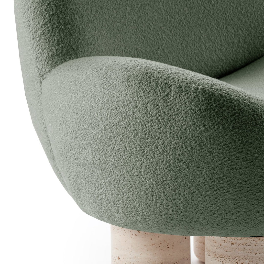 Soft green textured upholstery on a modern chair, with smooth cream-colored cylindrical legs.