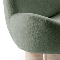 Soft green textured upholstery on a modern chair, with smooth cream-colored cylindrical legs.