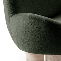 Textured dark green upholstery on a stylish chair with contrasting light stone legs.