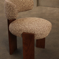 Textured beige upholstery with a speckled pattern, paired with dark wooden legs for a contemporary chair design.