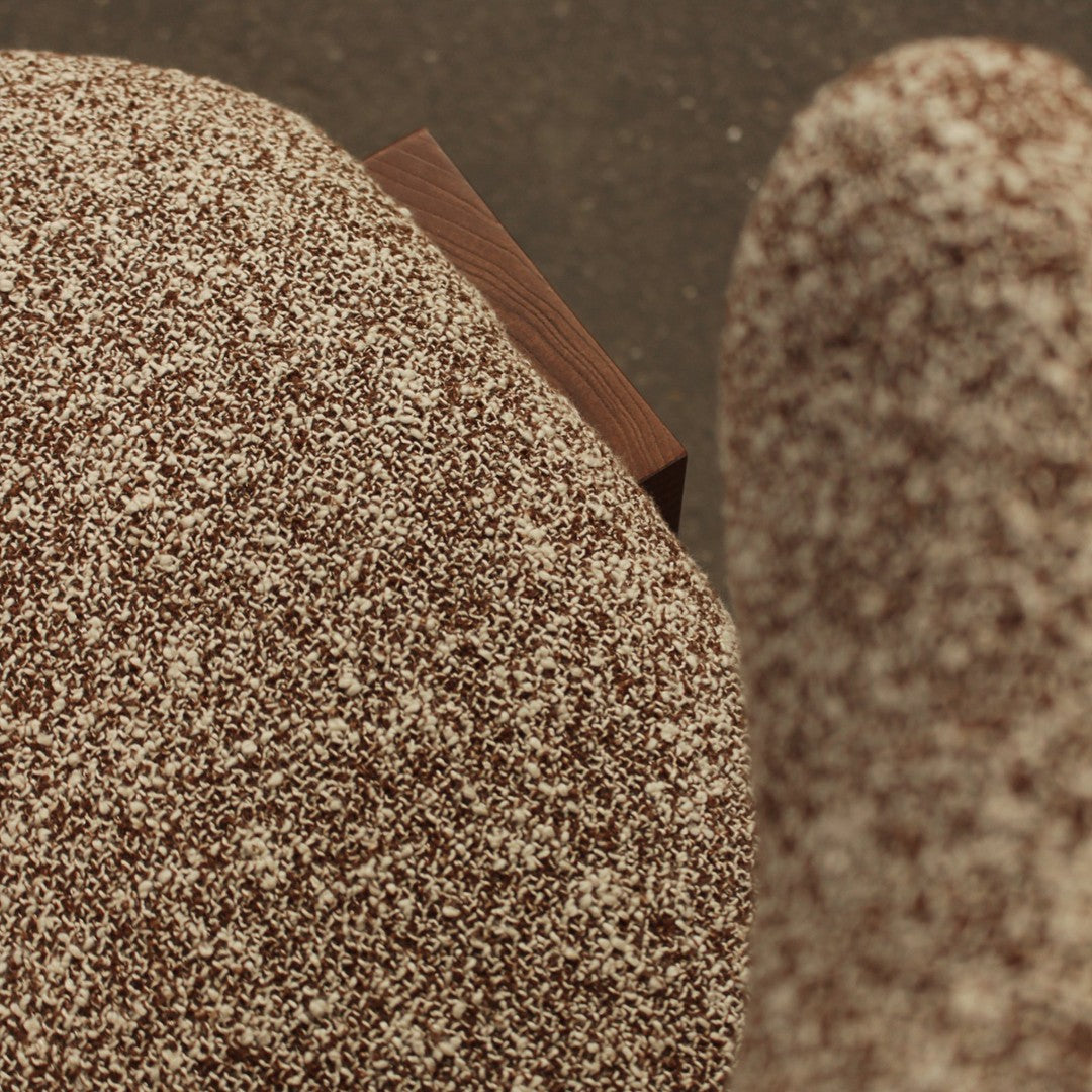 Brown speckled upholstery fabric with subtle texture, complemented by a wooden accent. Perfect for modern decor.