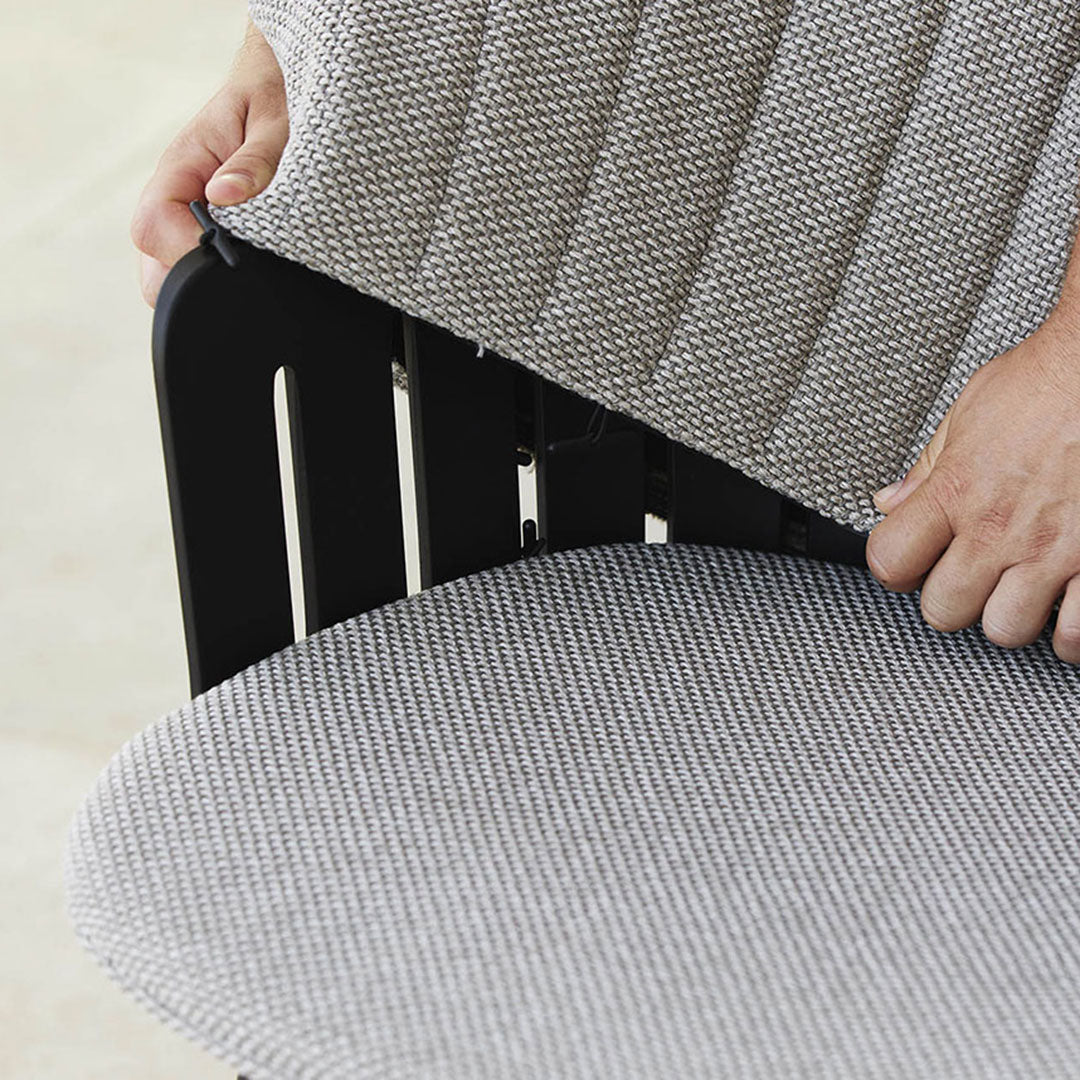 Gray striped fabric cushion on a black wooden chair, showcasing sleek patterns and modern design.