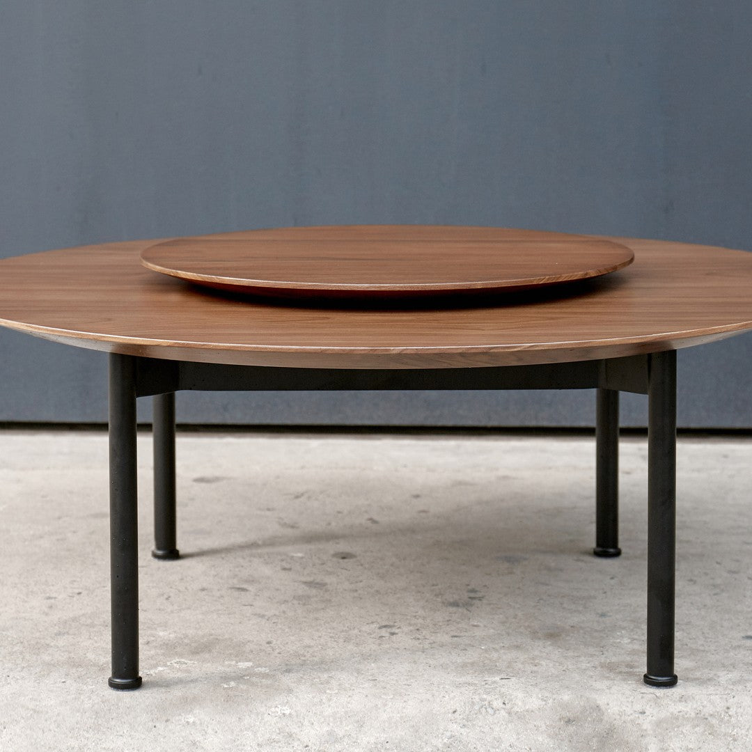 Round wooden coffee table with a rich brown finish and sleek black metal legs, featuring a modern two-tier design.