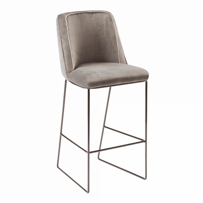 Gray velvet bar stool with silver nailhead trim and sleek metal legs, perfect for modern decor.