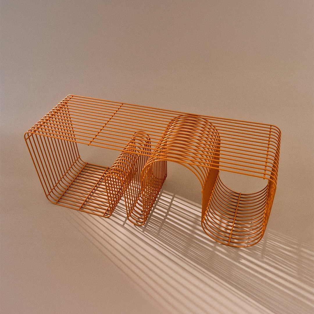 Orange wire table with a modern geometric design and shadows creating unique patterns on a light background.