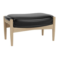 Black leather ottoman with light oak legs, featuring a smooth, sleek design and modern style. Ideal for contemporary decor.