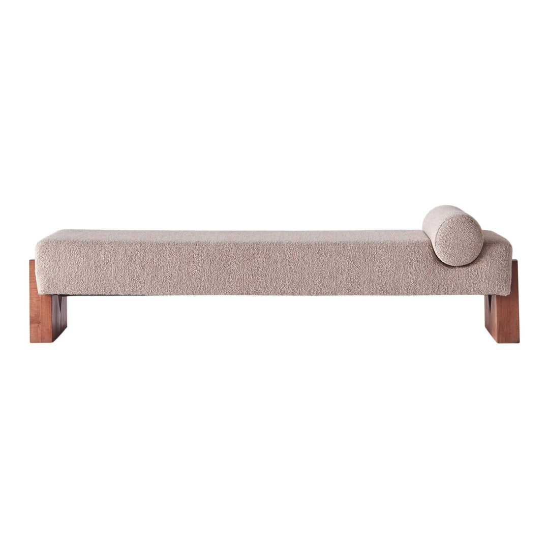 Beige fabric chaise lounge with a minimalist design and wooden legs, featuring a rounded bolster for added style.
