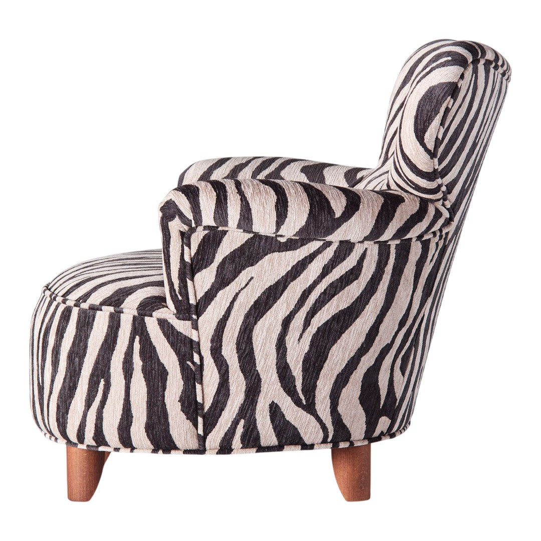 Zebra print armchair in black and cream with wooden legs, featuring bold stripes and modern design.