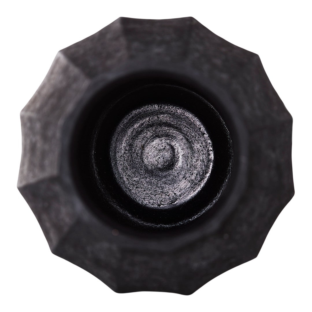 Close-up of a textured black bottle cap with a circular pattern at the center and a star-shaped outer design.