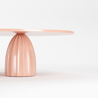 Round table with a smooth white top and a ribbed pastel pink base. Modern and stylish design.
