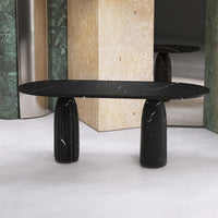 "Elegant black marble table with sleek, smooth surface and ribbed black columns, set against a neutral backdrop."