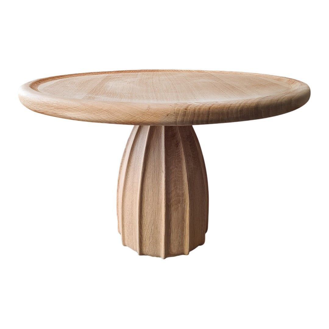 Round wooden table with a natural finish and ribbed pedestal base, showcasing warm tones and smooth textures.