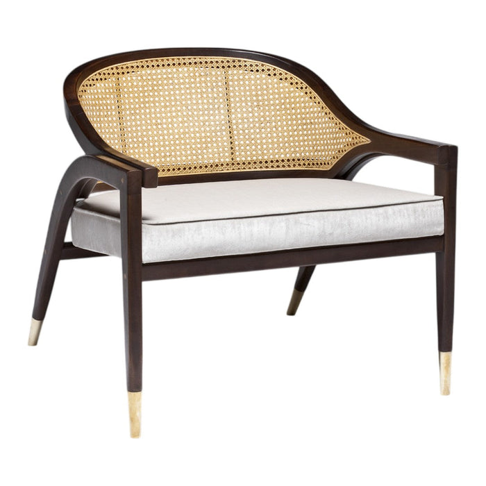Brown wooden armchair with cane backrest and beige cushion, featuring gold-tipped legs for a stylish contrast.