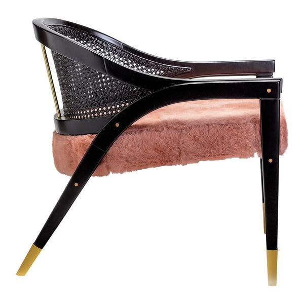 Black and gold accent chair with a pink faux fur cushion and a woven back, showcasing elegant modern design.