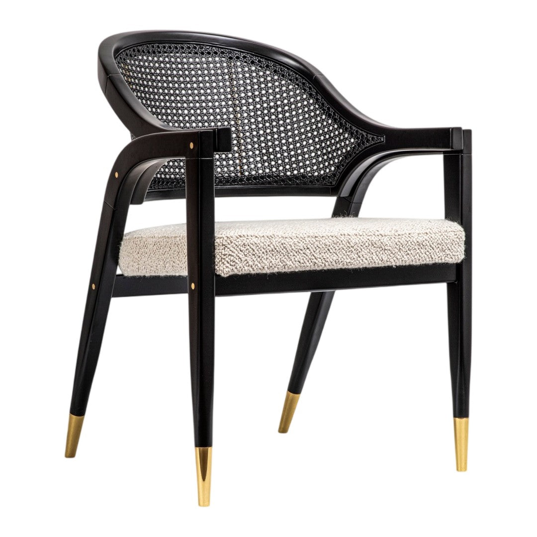 Black cane chair with textured beige cushion and gold-tipped legs, showcasing a modern, stylish design.