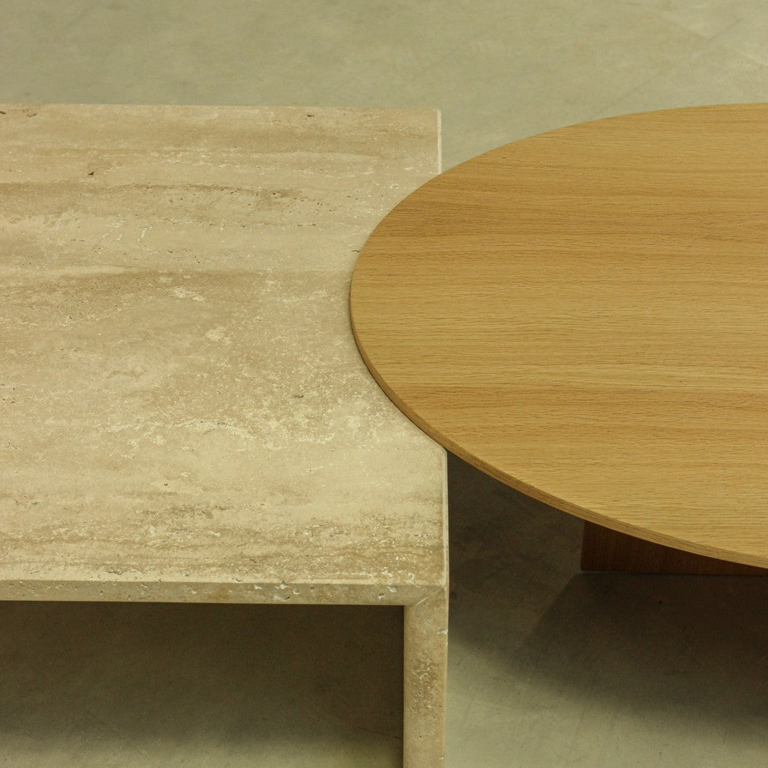 Light beige stone pattern table next to a smooth, warm wood grain round table on a neutral background.