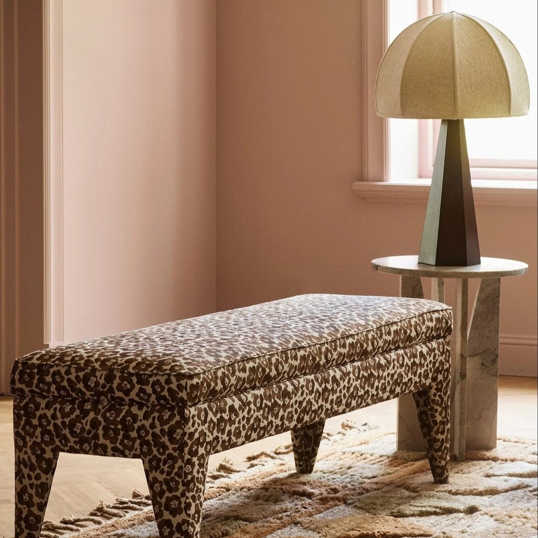 Leopard print bench in earthy tones, accented by a sleek, modern lamp and a textured rug.