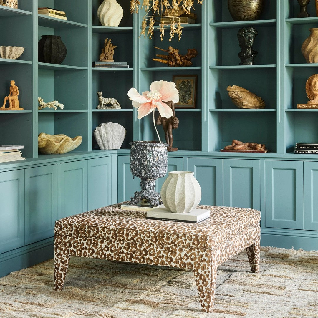 Leopard print coffee table in warm brown and beige, surrounded by a turquoise bookshelf and neutral decor elements.