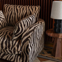 Zebra-striped couch in brown and cream tones, with contrasting solid color accents. Stylish textured fabric design.