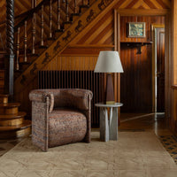 Textured brown chair with a subtle pattern, paired with a simple gray table and classic wood accents in a warm setting.