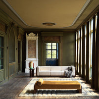 Elegant green walls with gold accents, complemented by a beige sofa and mustard yellow bench, featuring natural light.