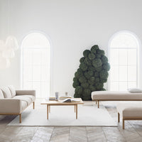 Beige sofas with light wood accents, white rug, and greenery create a modern, serene living space.
