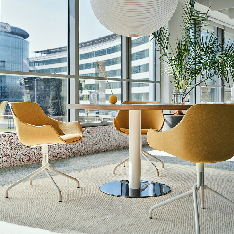 "Modern seating in warm mustard yellow with sleek white legs, complemented by a neutral beige rug and natural greenery."