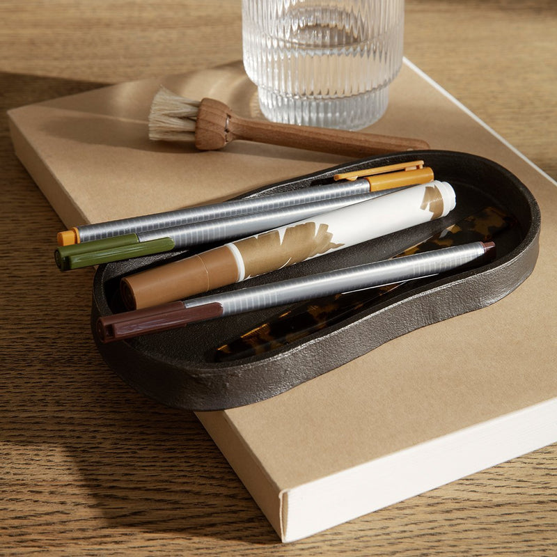 "Colorful pens in a dark tray with a tortoise shell pattern on a neutral background. Modern, minimalistic style."