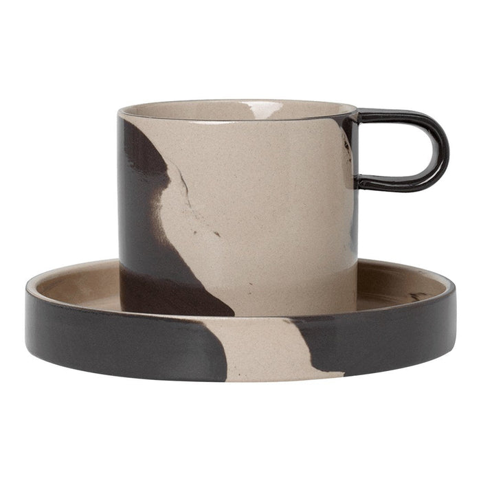 Stylish beige and black patterned cup with a matching saucer, featuring a modern, artistic design.