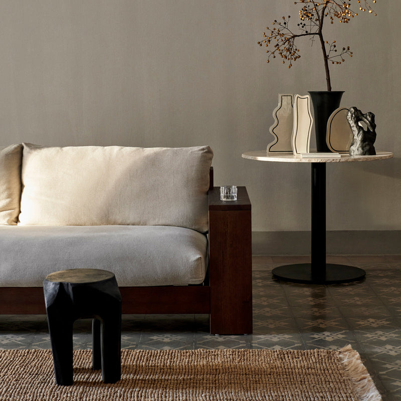 Beige sofa on a wood frame, black accent table, and decorative vases with neutral tones, set against a muted background.