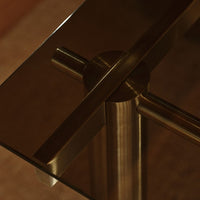 Brushed gold accents on sleek glass tabletop with a modern, minimalist design and subtle reflections.