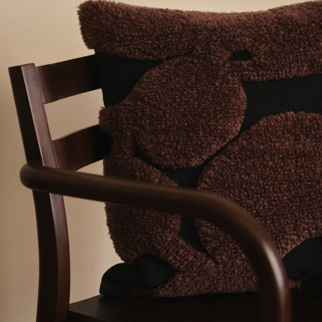 Textured brown and black pillow with abstract patterns, perfect for adding warmth and style to any space.