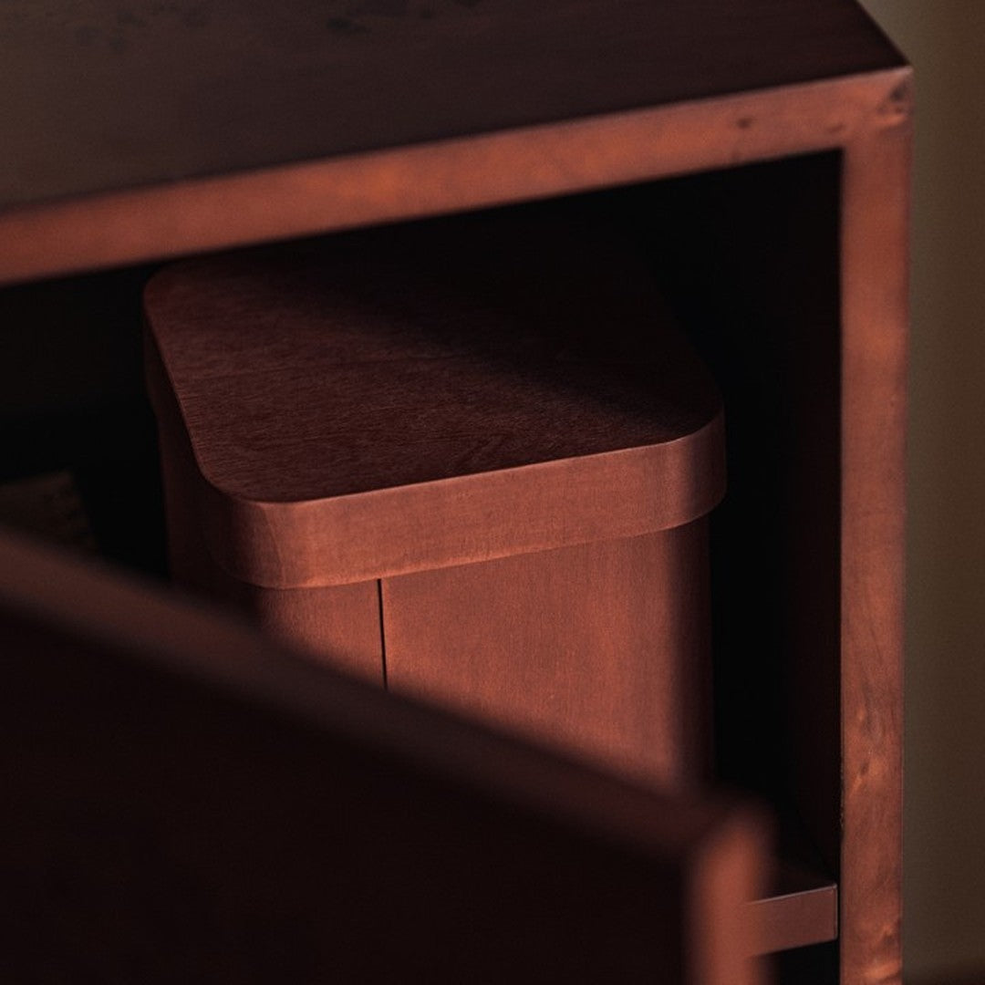 Brown storage container with a smooth finish, nestled in a dark wooden cabinet. Simple and modern design.