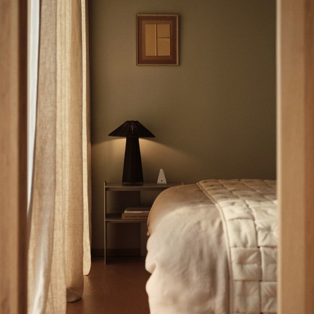 Warm earth tones with soft beige bedding and light brown curtains, complemented by geometric art and sleek lamp design.