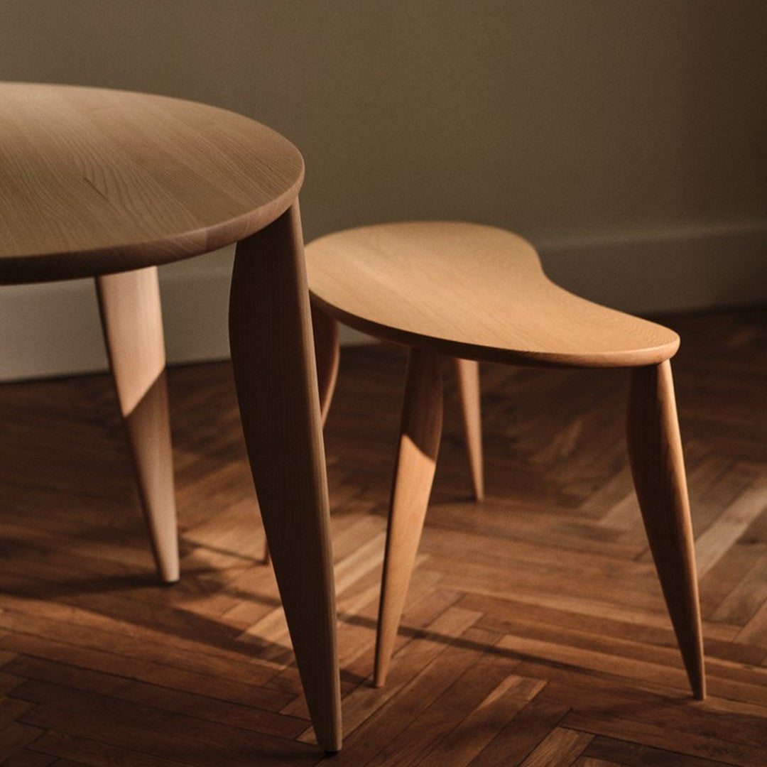 Light wood furniture featuring smooth finishes and elegant curves, set against a warm, patterned hardwood floor.